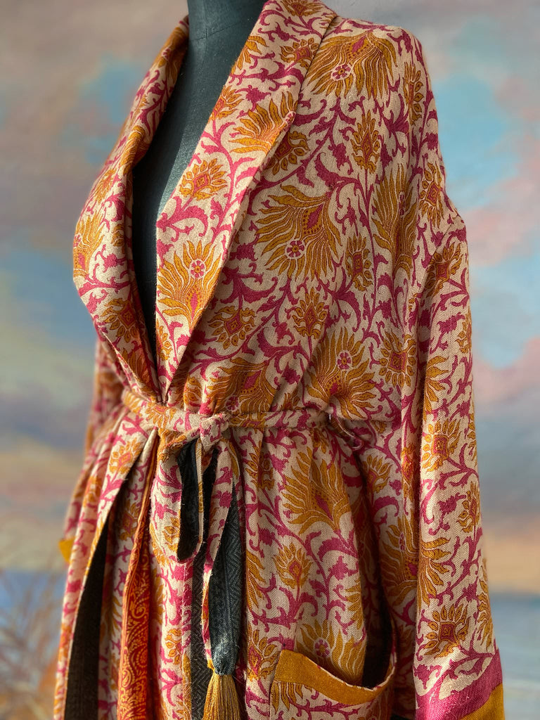 Saffron and hot pink fine wool dressing robe lined with silk. Wide sleeves, patch pockets and tassel sash belt. Bohemian styles sustainably created from antique and vintage textiles by the Pavilion Parade studio.