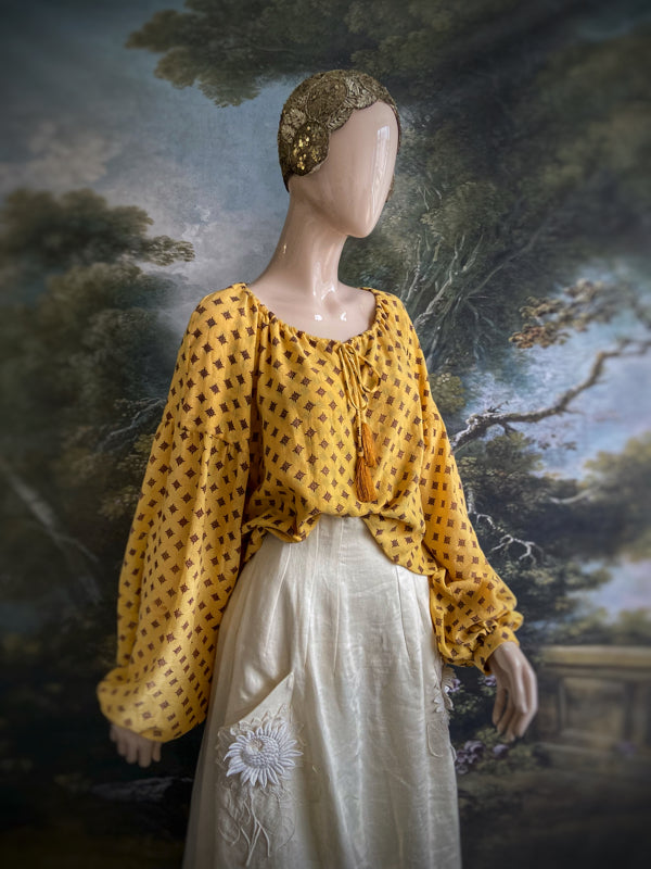 Saffron yellow cotton muslin block printed blouse with long full sleeves and adjustable drawstring neckline. Bohemian styles sustainably created from antique and vintage textiles by the Pavilion Parade studio. 