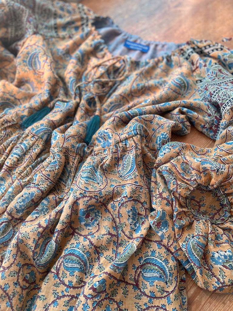 Faded ochre yellow and slate blue-grey cotton muslin block printed dress with long full sleeves and adjustable drawstring neckline. Bohemian styles sustainably created from antique and vintage textiles by the Pavilion Parade studio. 