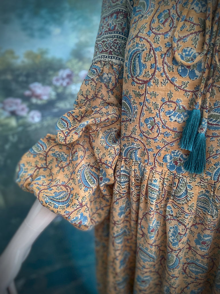 Faded ochre yellow and slate blue-grey cotton muslin block printed dress with long full sleeves and adjustable drawstring neckline. Bohemian styles sustainably created from antique and vintage textiles by the Pavilion Parade studio. 
