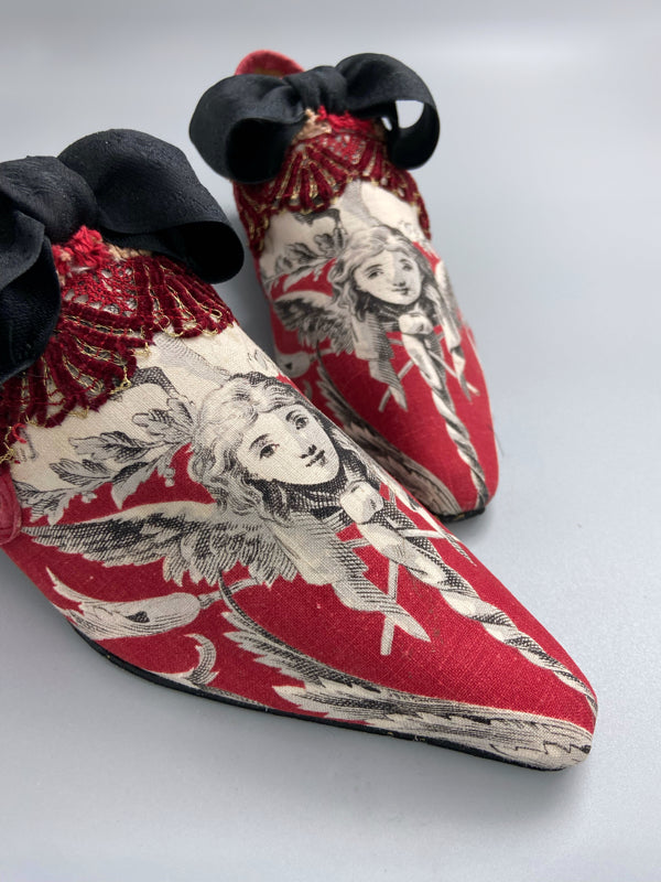 Red, black and white pointed toe bohemian shoes or slippers with a neo-classical winged god motif. Large black silk ribbon bows. Created from antique textiles by Pavilion Parade