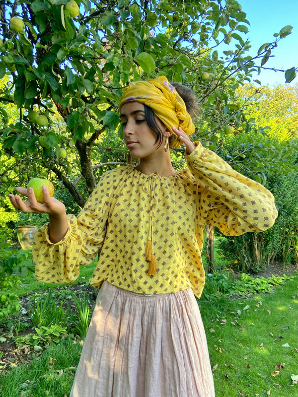 Saffron yellow cotton muslin block printed blouse with long full sleeves and adjustable drawstring neckline. Bohemian styles sustainably created from antique and vintage textiles by the Pavilion Parade studio. 