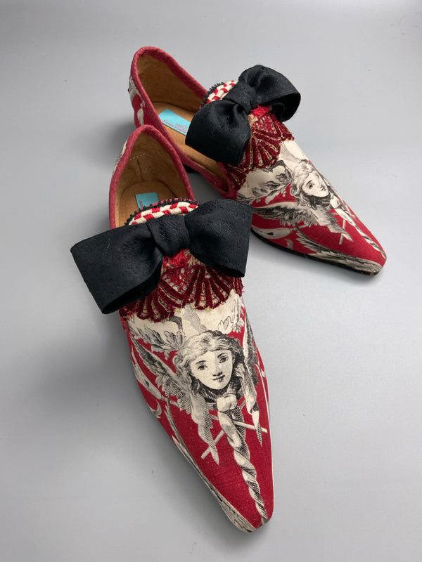 Red, black and white pointed toe bohemian shoes or slippers with a neo-classical winged god motif. Large black silk ribbon bows. Created from antique textiles by Pavilion Parade