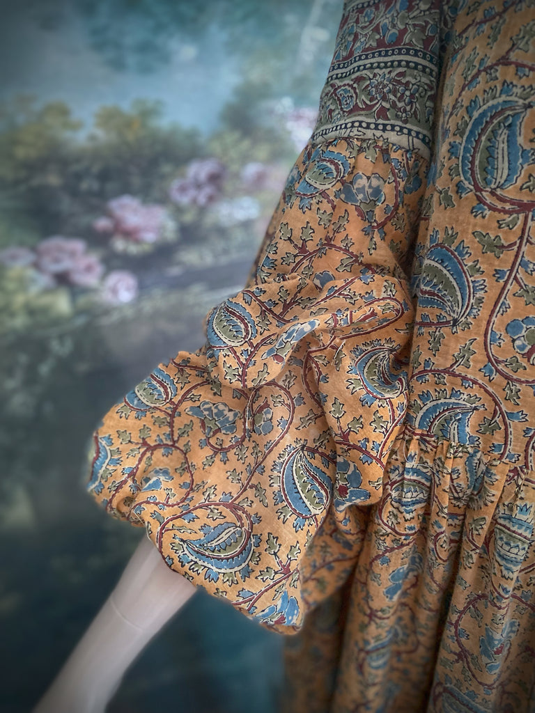 Faded ochre yellow and slate blue-grey cotton muslin block printed dress with long full sleeves and adjustable drawstring neckline. Bohemian styles sustainably created from antique and vintage textiles by the Pavilion Parade studio. 