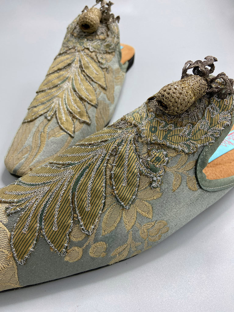 French grey silk brocade and 19th century metallic silver lace are used to create bohemian style shoes with hand worked antique acorn embellishment. Unique style by the Pavilion Parade studio.