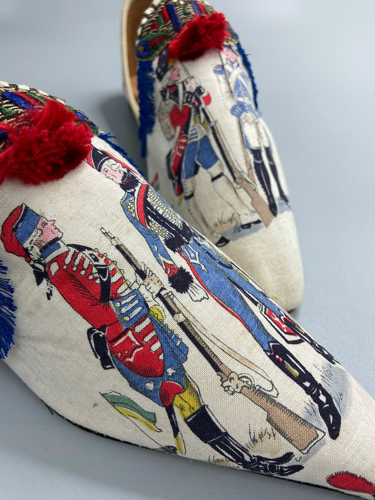 Historic military uniformed soldiers from a vintage French printed toile, and royal bue fringe with scarlet soutache pompom tassels are used to create unique bohemian shoes by Pavilion Parade