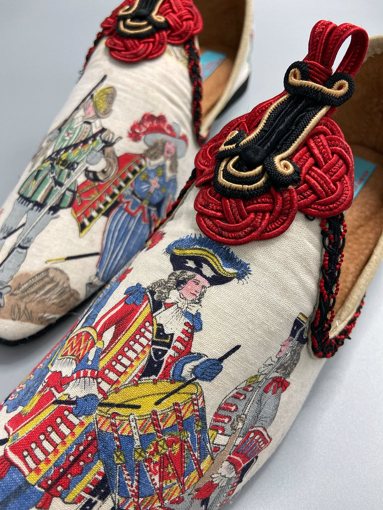 Historic military uniformed soldiers from a vintage French printed toile, and scarlet soutache frogging are used to create unique bohemian shoes by Pavilion Parade