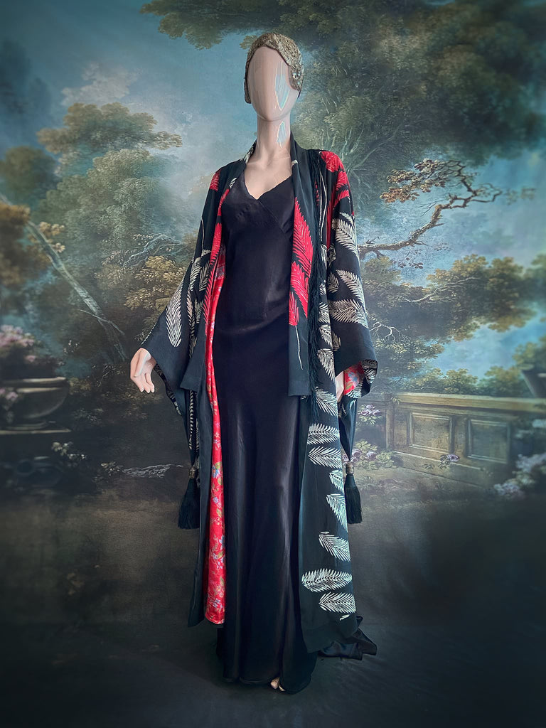 Full length 1920s inspired kimono robe with large patch pockets. Newly created from a crimson red and kohl black block print feather vintage crepe. Antique silk fringe on collar and large weighted tassels on sleeves. Fully lined in silk with French seams throughout. Bohemian styles sustainably created from antique and vintage textiles by the Pavilion Parade studio.