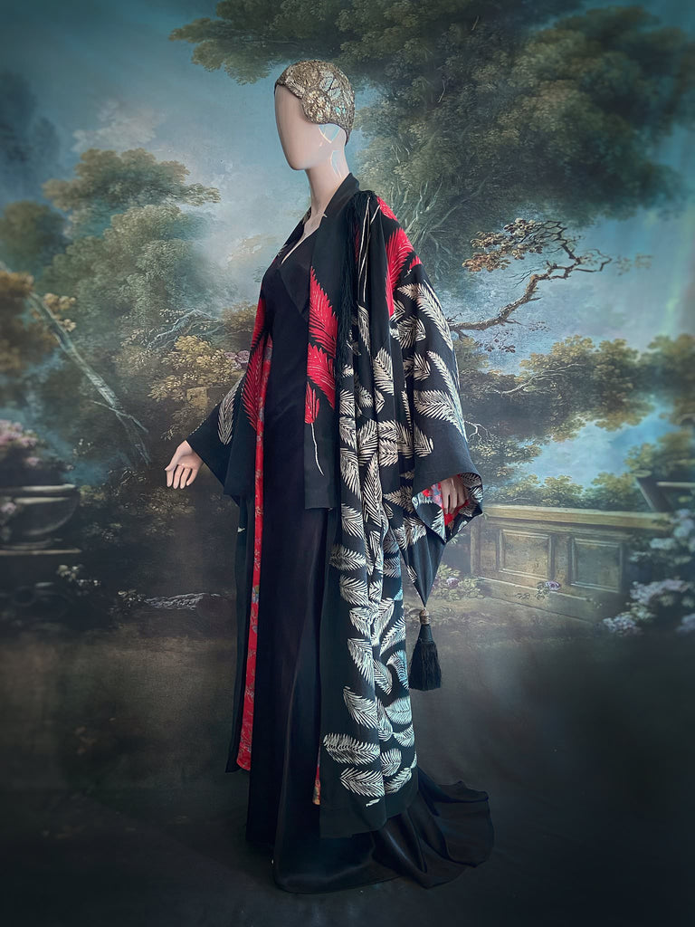 Full length 1920s inspired kimono robe with large patch pockets. Newly created from a crimson red and kohl black block print feather vintage crepe. Antique silk fringe on collar and large weighted tassels on sleeves. Fully lined in silk with French seams throughout. Bohemian styles sustainably created from antique and vintage textiles by the Pavilion Parade studio.