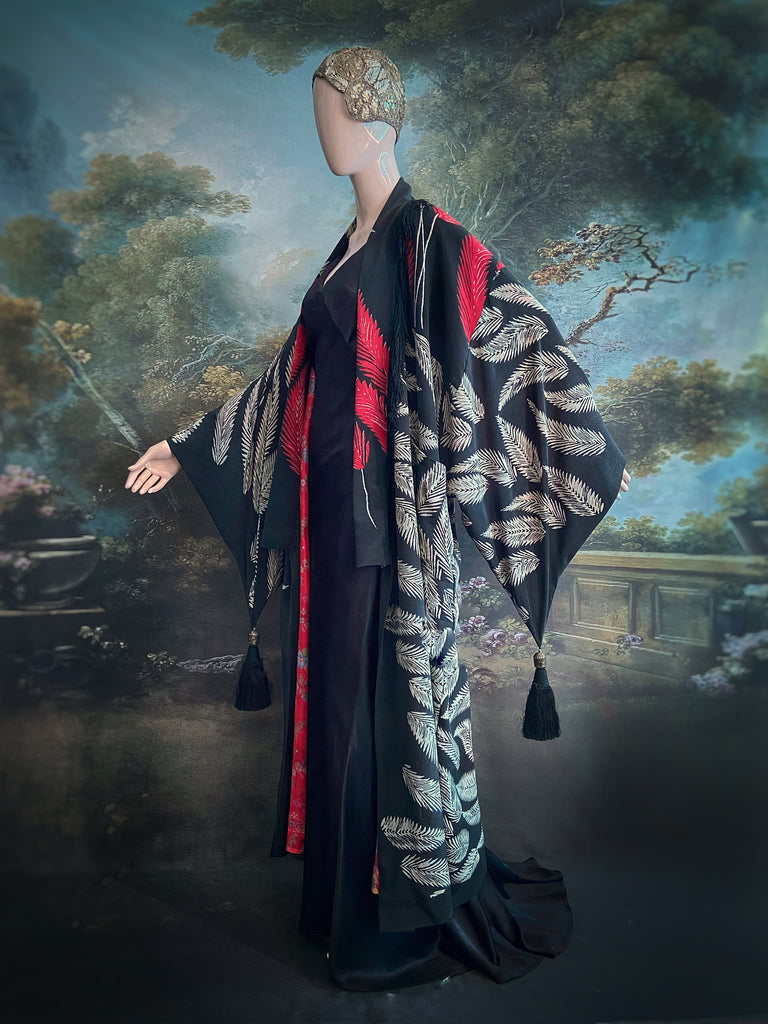Full length 1920s inspired kimono robe with large patch pockets. Newly created from a crimson red and kohl black block print feather vintage crepe. Antique silk fringe on collar and large weighted tassels on sleeves. Fully lined in silk with French seams throughout. Bohemian styles sustainably created from antique and vintage textiles by the Pavilion Parade studio.
