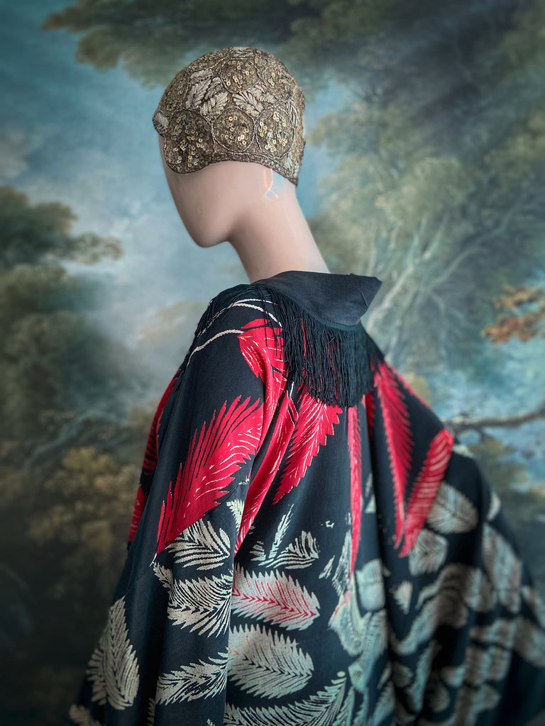 Full length 1920s inspired kimono robe with large patch pockets. Newly created from a crimson red and kohl black block print feather vintage crepe. Antique silk fringe on collar and large weighted tassels on sleeves. Fully lined in silk with French seams throughout. Bohemian styles sustainably created from antique and vintage textiles by the Pavilion Parade studio.