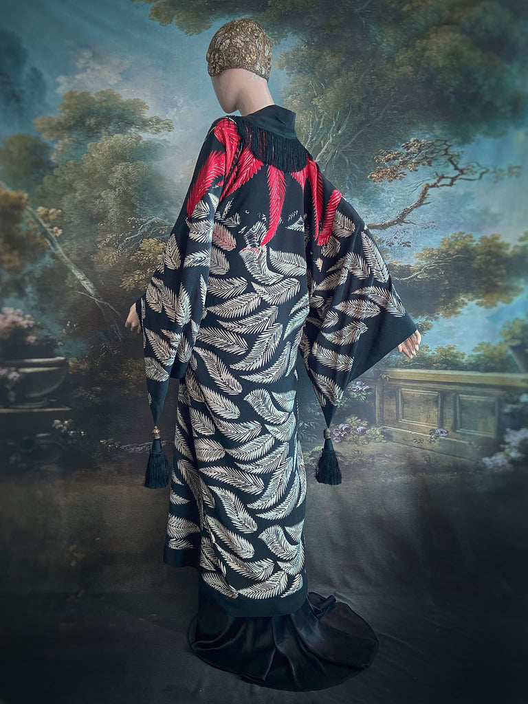 Full length 1920s inspired kimono robe with large patch pockets. Newly created from a crimson red and kohl black block print feather vintage crepe. Antique silk fringe on collar and large weighted tassels on sleeves. Fully lined in silk with French seams throughout. Bohemian styles sustainably created from antique and vintage textiles by the Pavilion Parade studio.