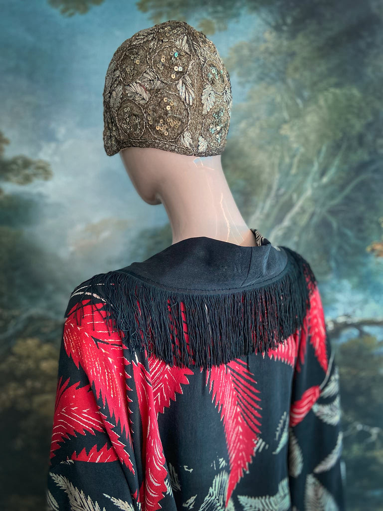Full length 1920s inspired kimono robe with large patch pockets. Newly created from a crimson red and kohl black block print feather vintage crepe. Antique silk fringe on collar and large weighted tassels on sleeves. Fully lined in silk with French seams throughout. Bohemian styles sustainably created from antique and vintage textiles by the Pavilion Parade studio.