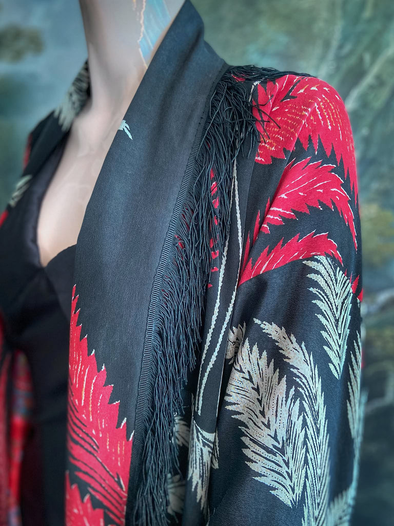 Full length 1920s inspired kimono robe with large patch pockets. Newly created from a crimson red and kohl black block print feather vintage crepe. Antique silk fringe on collar and large weighted tassels on sleeves. Fully lined in silk with French seams throughout. Bohemian styles sustainably created from antique and vintage textiles by the Pavilion Parade studio.