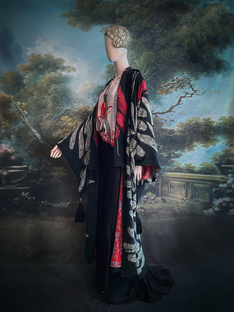 Full length 1920s inspired kimono robe with large patch pockets. Newly created from a crimson red and kohl black block print feather vintage crepe. Antique silk fringe on collar and large weighted tassels on sleeves. Fully lined in silk with French seams throughout. Bohemian styles sustainably created from antique and vintage textiles by the Pavilion Parade studio.