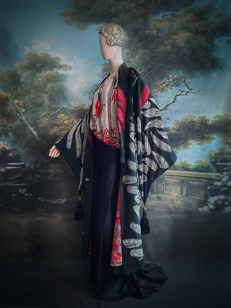 Full length 1920s inspired kimono robe with large patch pockets. Newly created from a crimson red and kohl black block print feather vintage crepe. Antique silk fringe on collar and large weighted tassels on sleeves. Fully lined in silk with French seams throughout. Bohemian styles sustainably created from antique and vintage textiles by the Pavilion Parade studio.