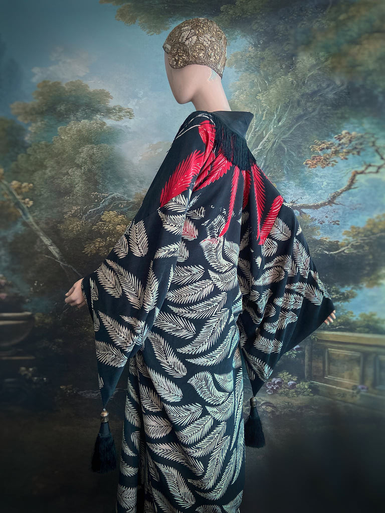Full length 1920s inspired kimono robe with large patch pockets. Newly created from a crimson red and kohl black block print feather vintage crepe. Antique silk fringe on collar and large weighted tassels on sleeves. Fully lined in silk with French seams throughout. Bohemian styles sustainably created from antique and vintage textiles by the Pavilion Parade studio.