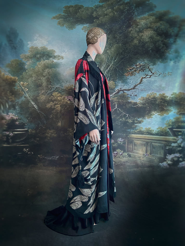 Full length 1920s inspired kimono robe with large patch pockets. Newly created from a crimson red and kohl black block print feather vintage crepe. Antique silk fringe on collar and large weighted tassels on sleeves. Fully lined in silk with French seams throughout. Bohemian styles sustainably created from antique and vintage textiles by the Pavilion Parade studio.
