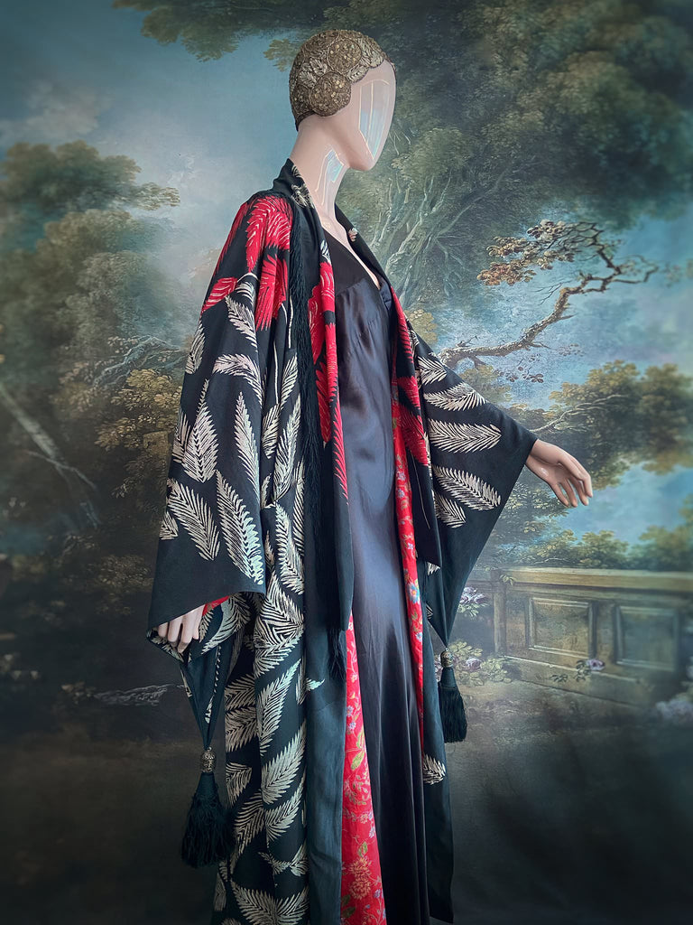 Full length 1920s inspired kimono robe with large patch pockets. Newly created from a crimson red and kohl black block print feather vintage crepe. Antique silk fringe on collar and large weighted tassels on sleeves. Fully lined in silk with French seams throughout. Bohemian styles sustainably created from antique and vintage textiles by the Pavilion Parade studio.