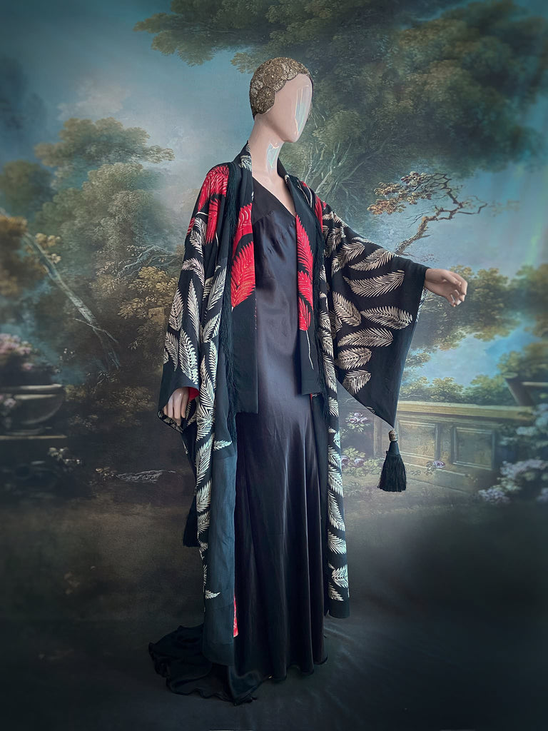 Full length 1920s inspired kimono robe with large patch pockets. Newly created from a crimson red and kohl black block print feather vintage crepe. Antique silk fringe on collar and large weighted tassels on sleeves. Fully lined in silk with French seams throughout. Bohemian styles sustainably created from antique and vintage textiles by the Pavilion Parade studio.