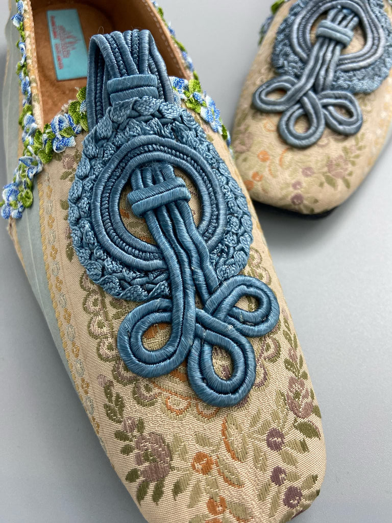 Pale blue and ivory silk brocade Regency inspired dancing slippers with rococo ribbon trim. Embellished with dusty blue antique soutache cord medallions. Bohemian styles created from antique textiles by the Pavilion Parade studio. 