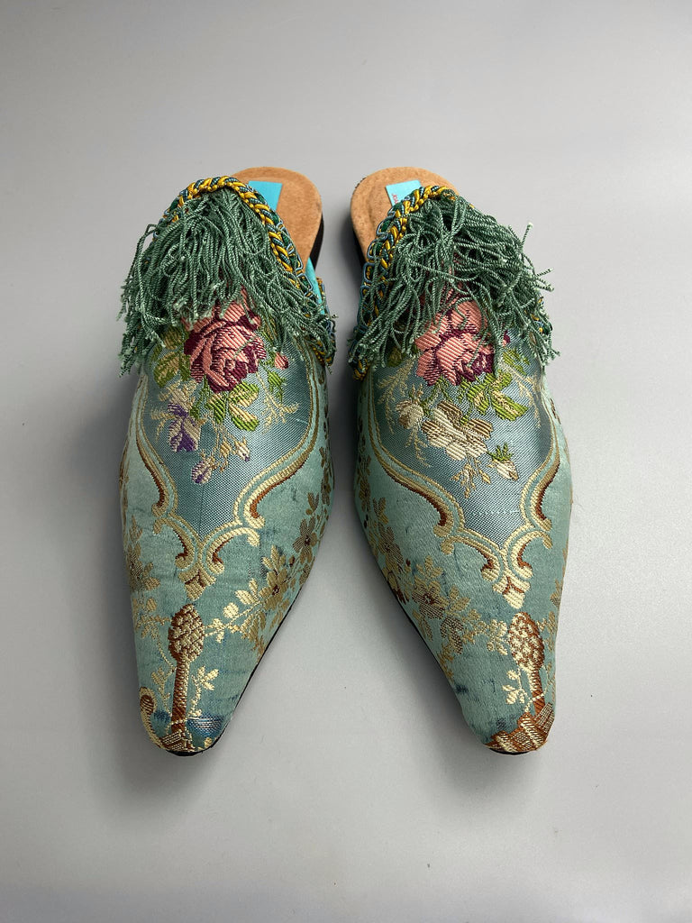 Faded sky blue silk pointed toe shoes with pink roses in the Georgian style. Embellished with silk tassel fringe and antique braids. Bohemian styles sustainably created from antique textiles by Pavilion Parade.