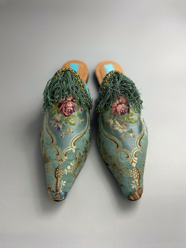 Faded sky blue silk pointed toe shoes with pink roses in the Georgian style. Embellished with silk tassel fringe and antique braids. Bohemian styles sustainably created from antique textiles by Pavilion Parade.