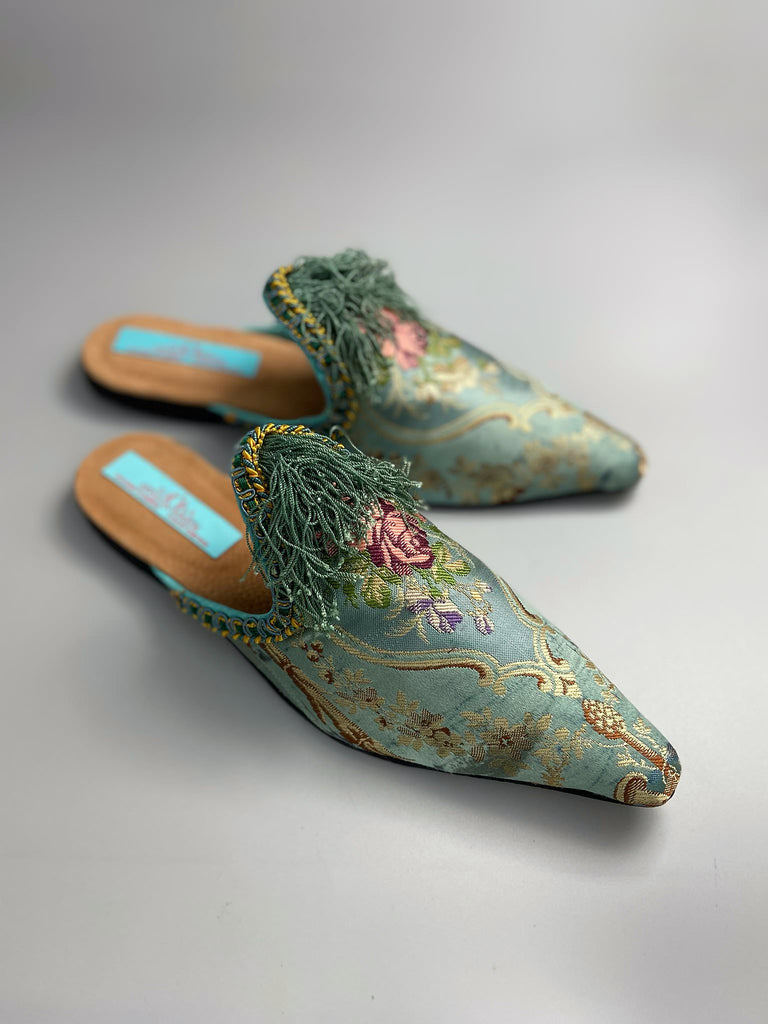 Faded sky blue silk pointed toe shoes with pink roses in the Georgian style. Embellished with silk tassel fringe and antique braids. Bohemian styles sustainably created from antique textiles by Pavilion Parade.