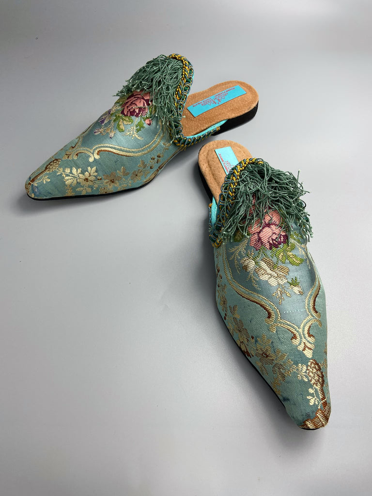 Faded sky blue silk pointed toe shoes with pink roses in the Georgian style. Embellished with silk tassel fringe and antique braids. Bohemian styles sustainably created from antique textiles by Pavilion Parade.