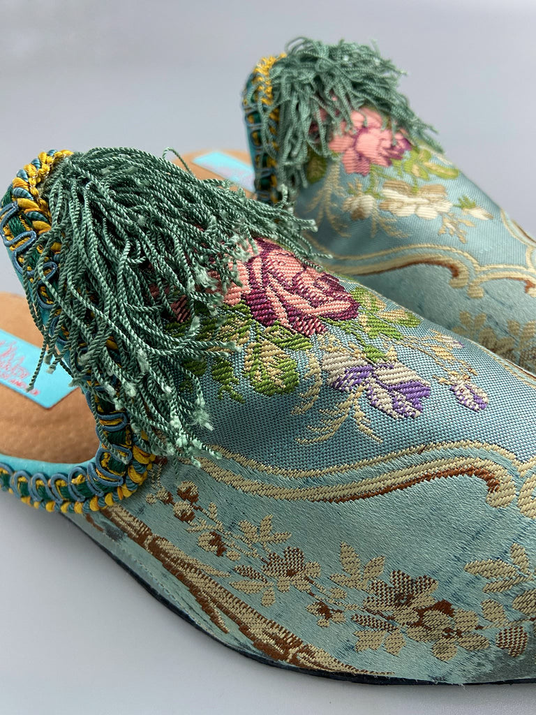 Faded sky blue silk pointed toe shoes with pink roses in the Georgian style. Embellished with silk tassel fringe and antique braids. Bohemian styles sustainably created from antique textiles by Pavilion Parade.