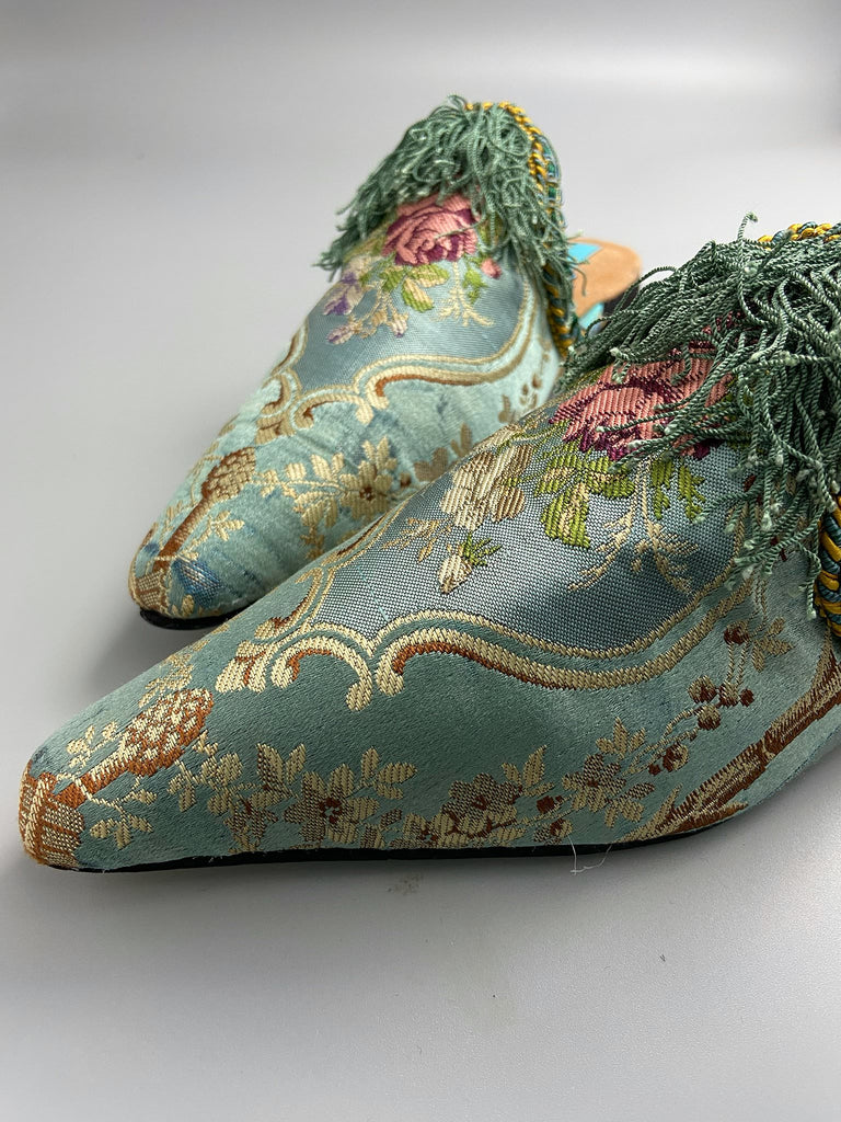 Faded sky blue silk pointed toe shoes with pink roses in the Georgian style. Embellished with silk tassel fringe and antique braids. Bohemian styles sustainably created from antique textiles by Pavilion Parade.