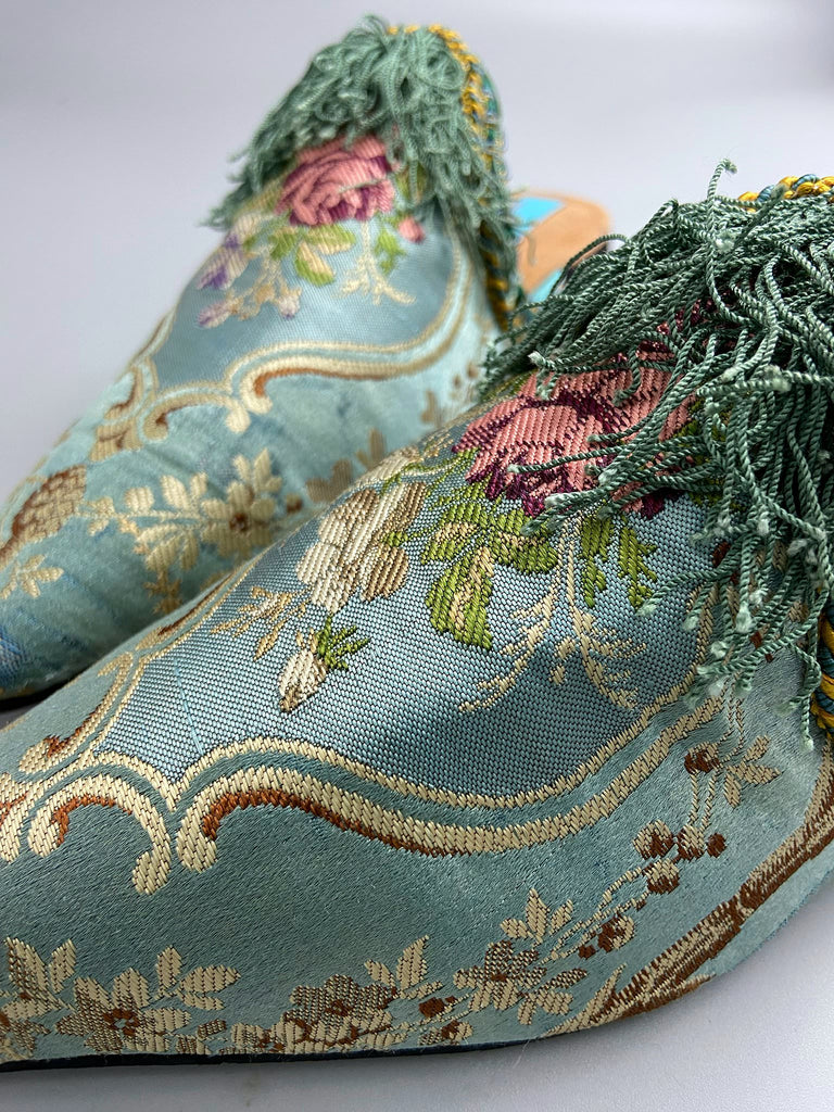 Faded sky blue silk pointed toe shoes with pink roses in the Georgian style. Embellished with silk tassel fringe and antique braids. Bohemian styles sustainably created from antique textiles by Pavilion Parade.