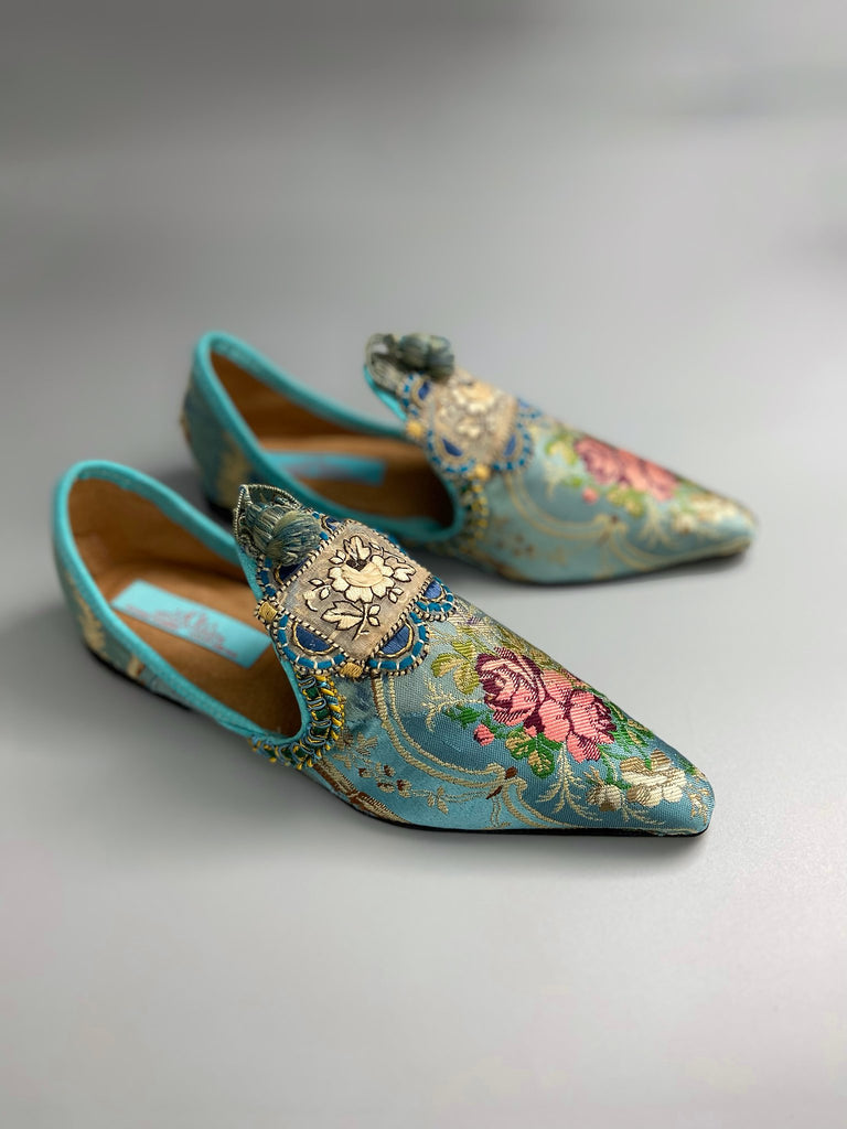 Faded sky blue silk pointed toe shoes with pink roses in the Georgian style. Embellished with silk embroidered appliqués and antique braids. Bohemian styles sustainably created from antique textiles by Pavilion Parade.