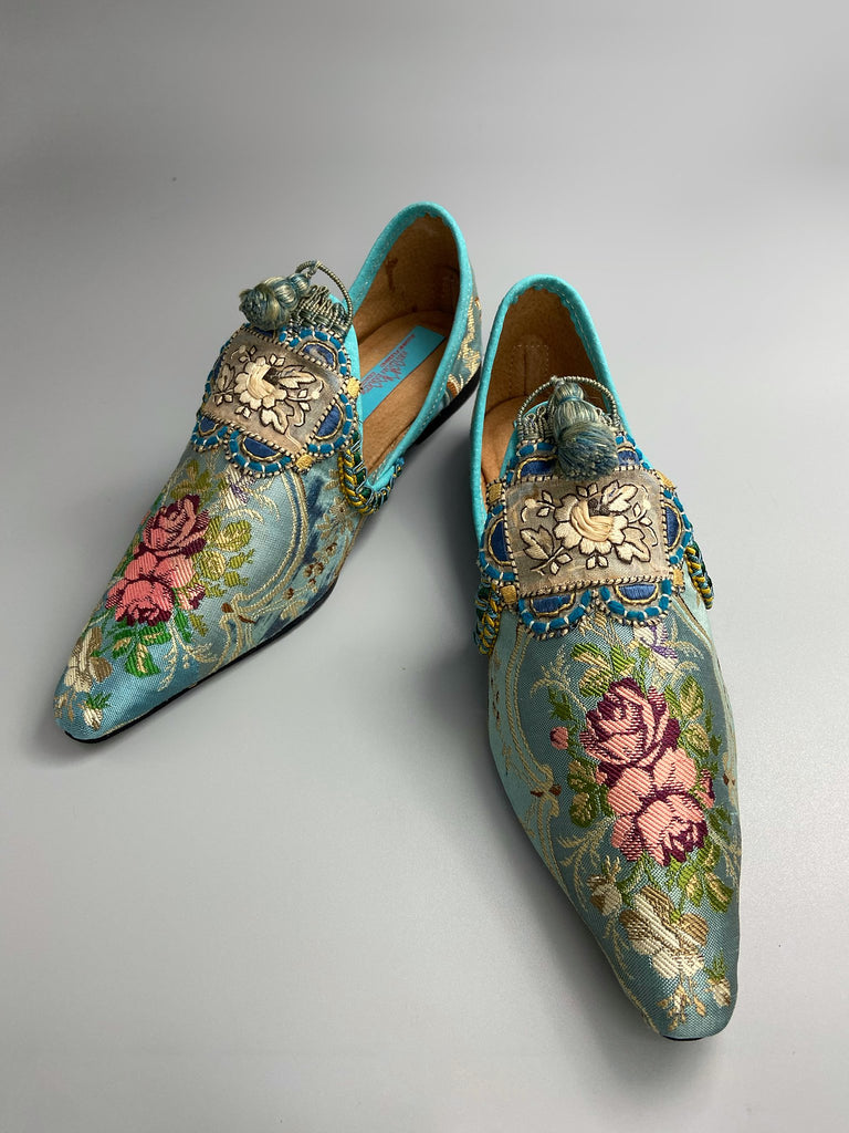 Faded sky blue silk pointed toe shoes with pink roses in the Georgian style. Embellished with silk tassel fringe and antique braids. Bohemian styles sustainably created from antique textiles by Pavilion Parade.