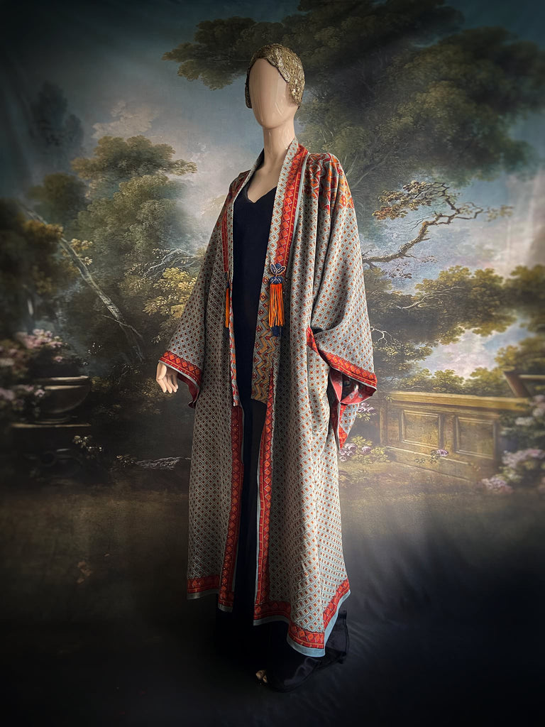 Full length 1920s inspired kimono robe with large patch pockets and antique Art Deco beaded tassels. Newly created from a dusty slate blue, rust and mustard vintage silk crepe with silver wire Mukesh work detail. Fully lined in silk with French seams throughout. Bohemian styles sustainably created from antique and vintage textiles by the Pavilion Parade studio.