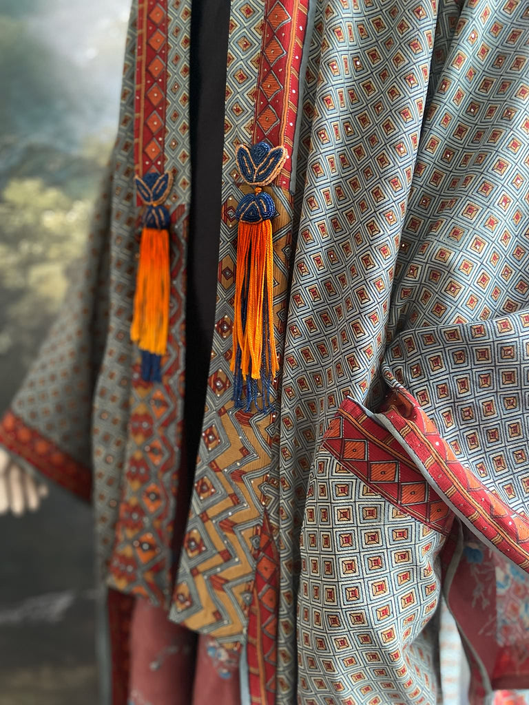 Full length 1920s inspired kimono robe with large patch pockets and antique Art Deco beaded tassels. Newly created from a dusty slate blue, rust and mustard vintage silk crepe with silver wire Mukesh work detail. Fully lined in silk with French seams throughout. Bohemian styles sustainably created from antique and vintage textiles by the Pavilion Parade studio.