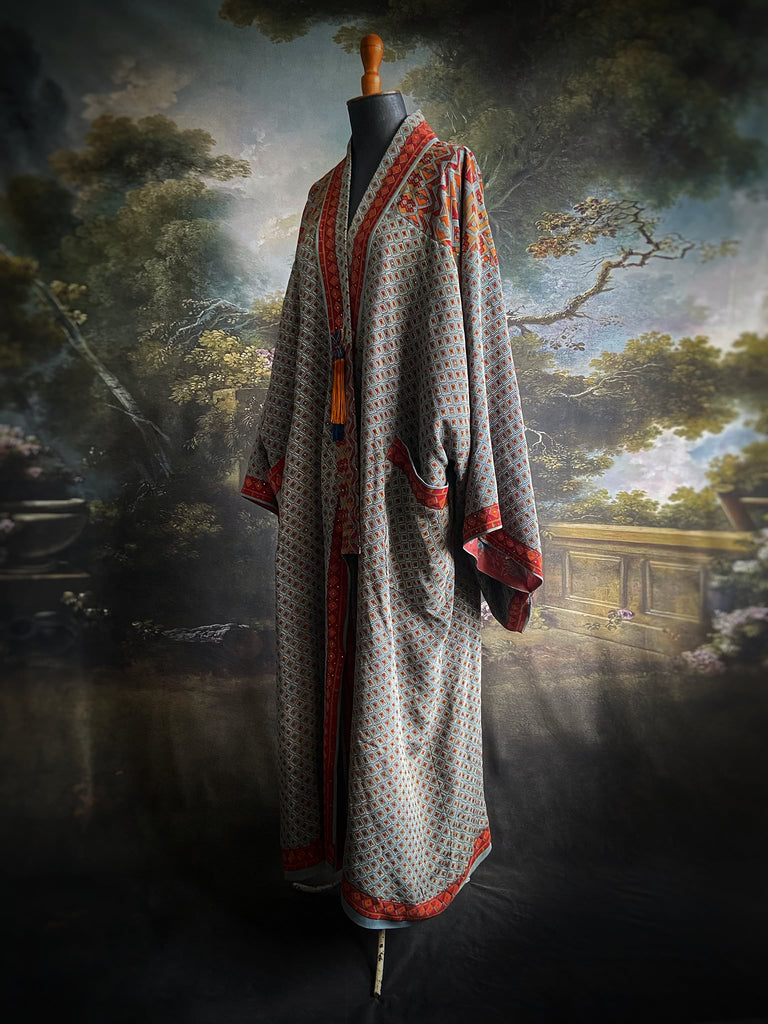 Full length 1920s inspired kimono robe with large patch pockets and antique Art Deco beaded tassels. Newly created from a dusty slate blue, rust and mustard vintage silk crepe with silver wire Mukesh work detail. Fully lined in silk with French seams throughout. Bohemian styles sustainably created from antique and vintage textiles by the Pavilion Parade studio.