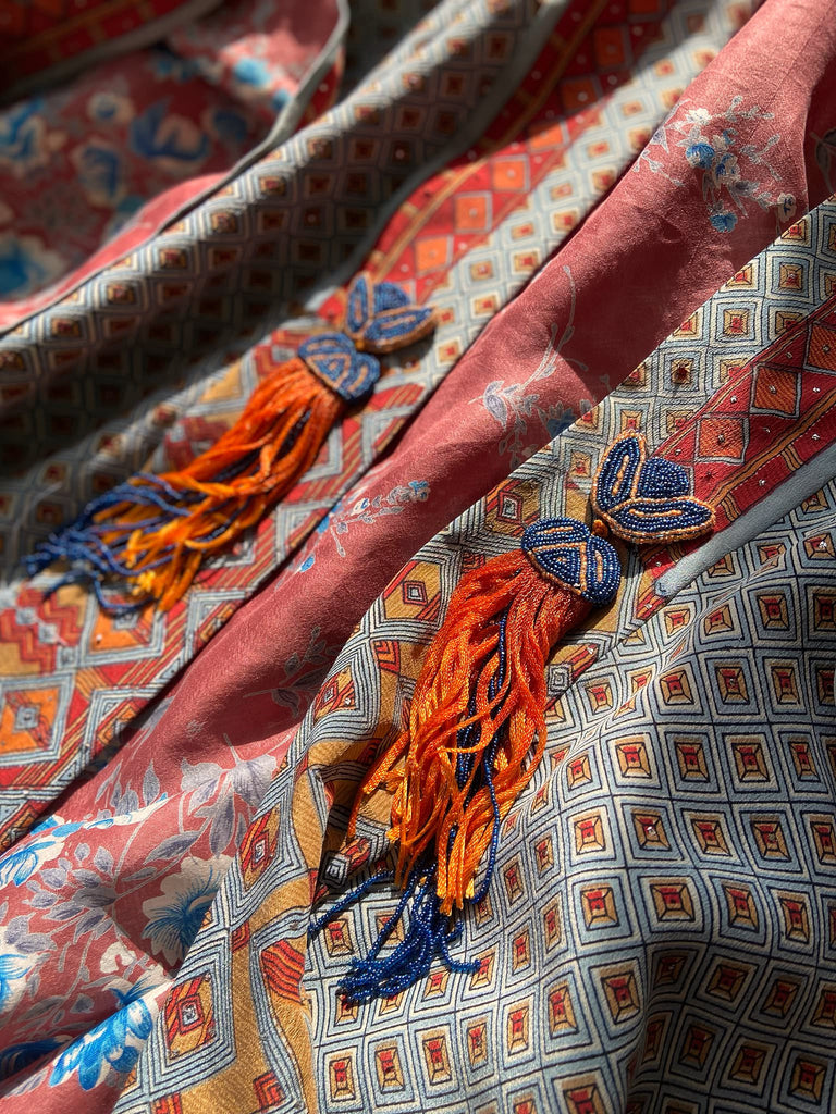 Full length 1920s inspired kimono robe with large patch pockets and antique Art Deco beaded tassels. Newly created from a dusty slate blue, rust and mustard vintage silk crepe with silver wire Mukesh work detail. Fully lined in silk with French seams throughout. Bohemian styles sustainably created from antique and vintage textiles by the Pavilion Parade studio.