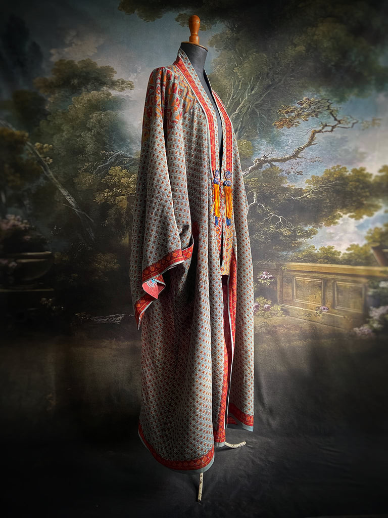 Full length 1920s inspired kimono robe with large patch pockets and antique Art Deco beaded tassels. Newly created from a dusty slate blue, rust and mustard vintage silk crepe with silver wire Mukesh work detail. Fully lined in silk with French seams throughout. Bohemian styles sustainably created from antique and vintage textiles by the Pavilion Parade studio.