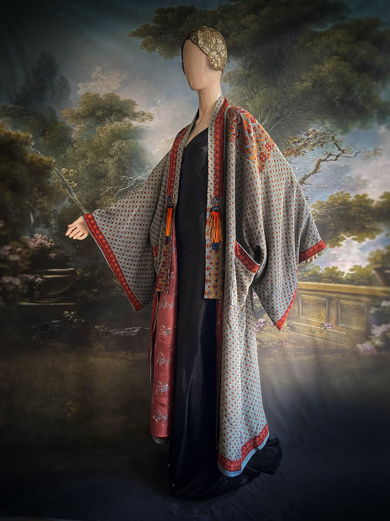 Full length 1920s inspired kimono robe with large patch pockets and antique Art Deco beaded tassels. Newly created from a dusty slate blue, rust and mustard vintage silk crepe with silver wire Mukesh work detail. Fully lined in silk with French seams throughout. Bohemian styles sustainably created from antique and vintage textiles by the Pavilion Parade studio.