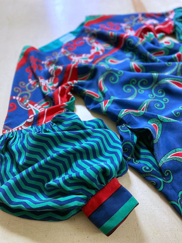 Silk crepe shift dress with pockets and volume long sleeves gathered in to fitted cuffs. Bold grphic print in shades of cobalt blue, teal and scarlet.  Unique garments sustainably created from vintage textiles by the Pavilion Parade studio.