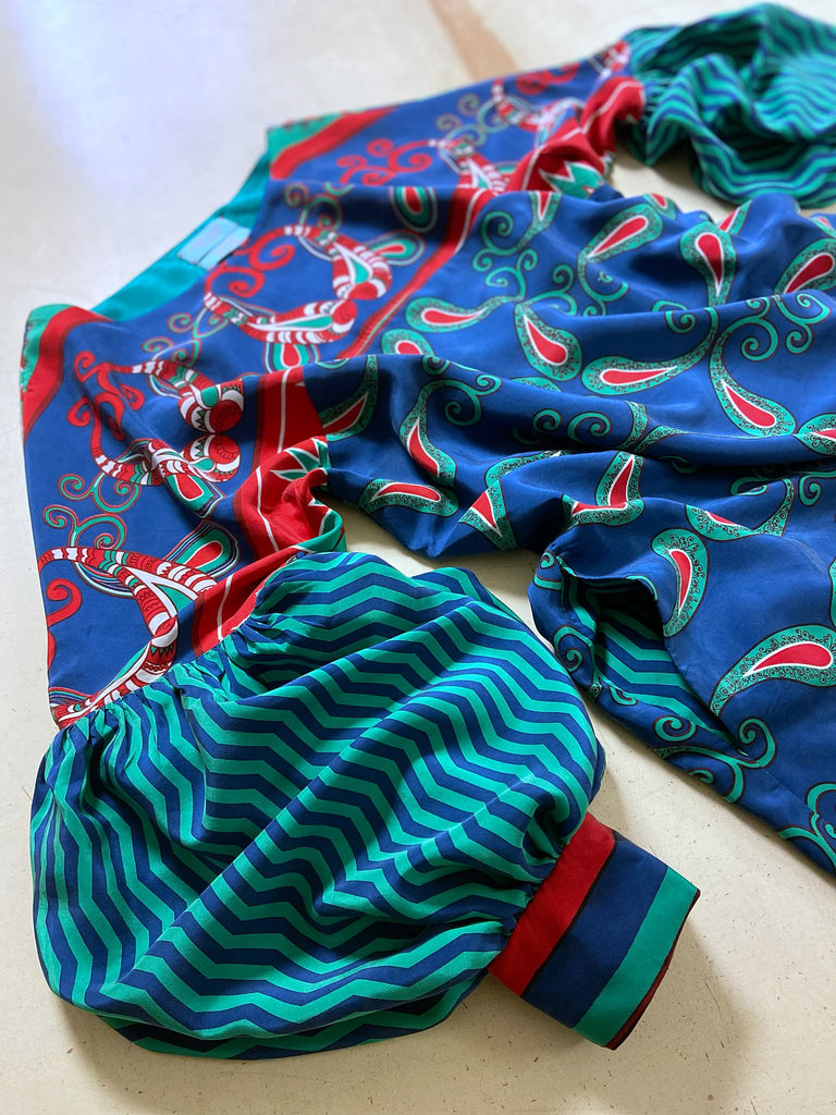 Silk crepe shift dress with pockets and volume long sleeves gathered in to fitted cuffs. Bold grphic print in shades of cobalt blue, teal and scarlet.  Unique garments sustainably created from vintage textiles by the Pavilion Parade studio.