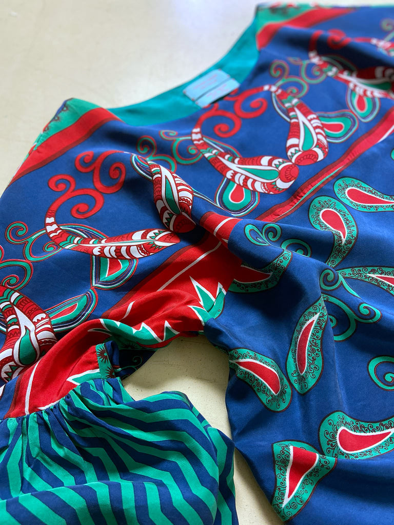 Silk crepe shift dress with pockets and volume long sleeves gathered in to fitted cuffs. Bold grphic print in shades of cobalt blue, teal and scarlet.  Unique garments sustainably created from vintage textiles by the Pavilion Parade studio.