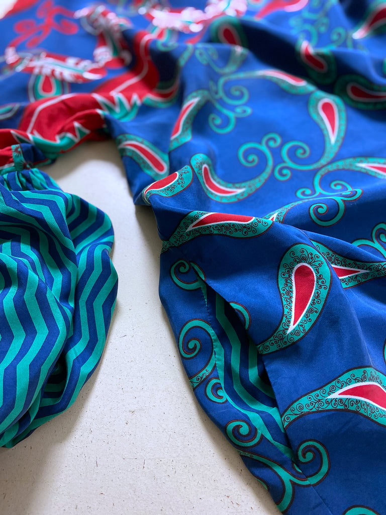 Silk crepe shift dress with pockets and volume long sleeves gathered in to fitted cuffs. Bold grphic print in shades of cobalt blue, teal and scarlet.  Unique garments sustainably created from vintage textiles by the Pavilion Parade studio.