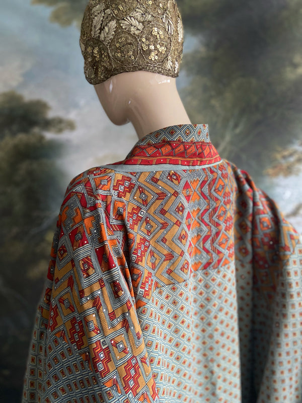 Full length 1920s inspired kimono robe with large patch pockets and antique Art Deco beaded tassels. Newly created from a dusty slate blue, rust and mustard vintage silk crepe with silver wire Mukesh work detail. Fully lined in silk with French seams throughout. Bohemian styles sustainably created from antique and vintage textiles by the Pavilion Parade studio.
