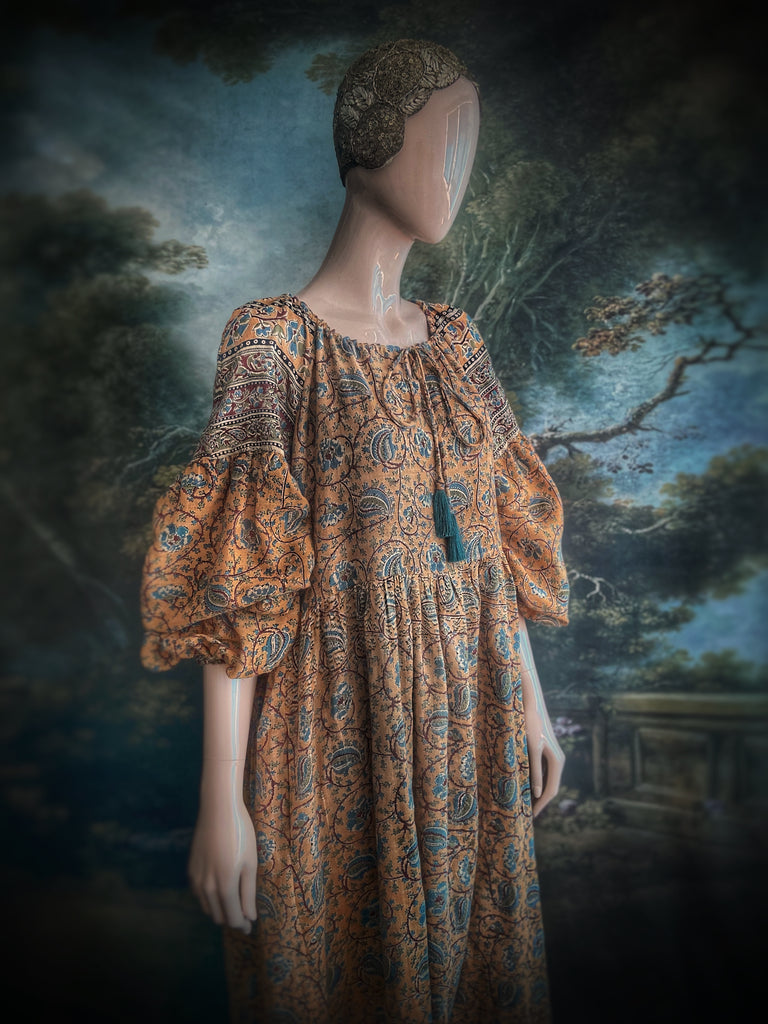 Faded ochre yellow and slate blue-grey cotton muslin block printed dress with long full sleeves and adjustable drawstring neckline. Bohemian styles sustainably created from antique and vintage textiles by the Pavilion Parade studio. 