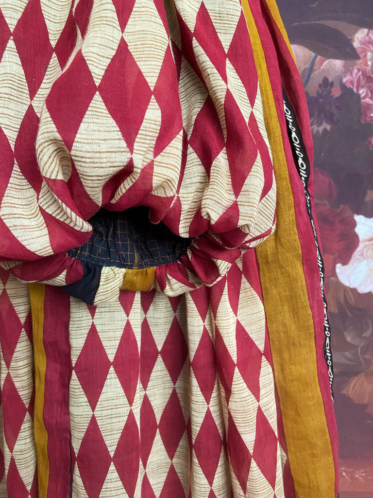 Harlequin red, yellow and black volume dress with long full sleeves and pockets. Bohemian style sustainably created from antique and vintage textiles by the Pavilion Parade studio