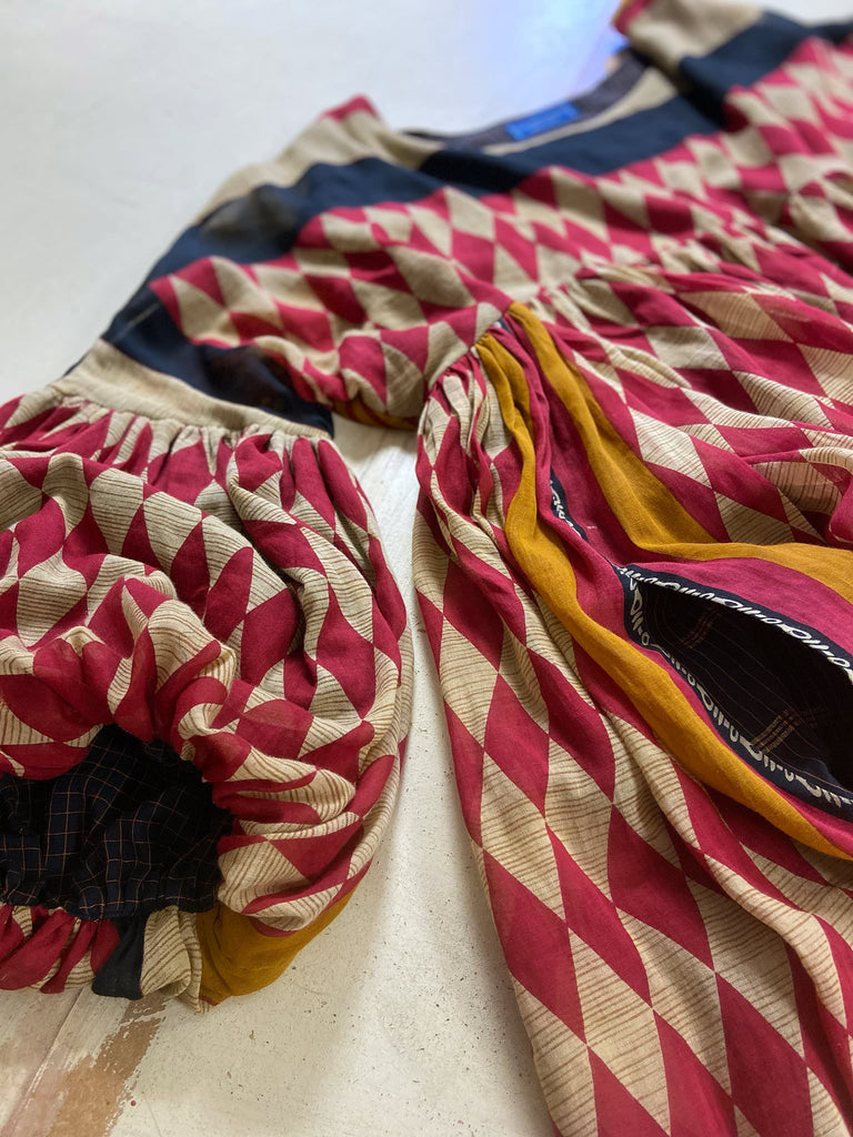 Harlequin red, yellow and black volume dress with long full sleeves and pockets. Bohemian style sustainably created from antique and vintage textiles by the Pavilion Parade studio