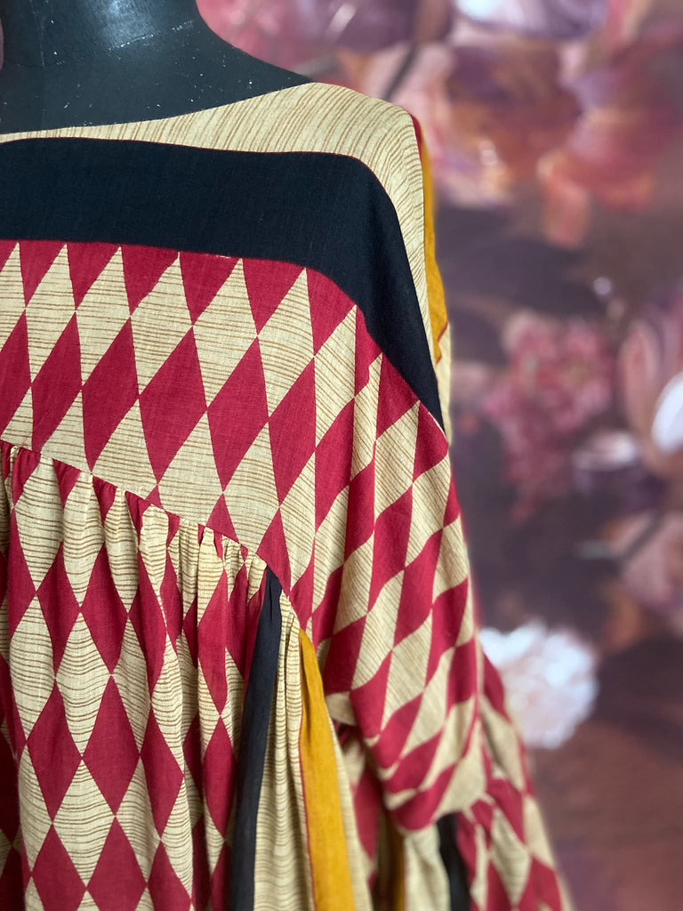 Harlequin red, yellow and black volume dress with long full sleeves and pockets. Bohemian style sustainably created from antique and vintage textiles by the Pavilion Parade studio