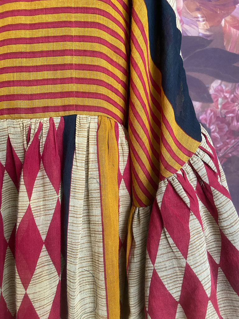 Harlequin red, yellow and black volume dress with long full sleeves and pockets. Bohemian style sustainably created from antique and vintage textiles by the Pavilion Parade studio